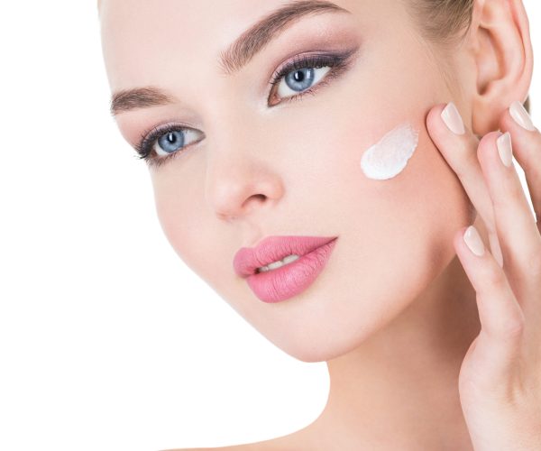 Young woman applies cosmetic cream on a face. Y Young beautiful woman with health fresh face. Beauty treatment concept. Skin care. Pretty female with health, fresh skin of body.